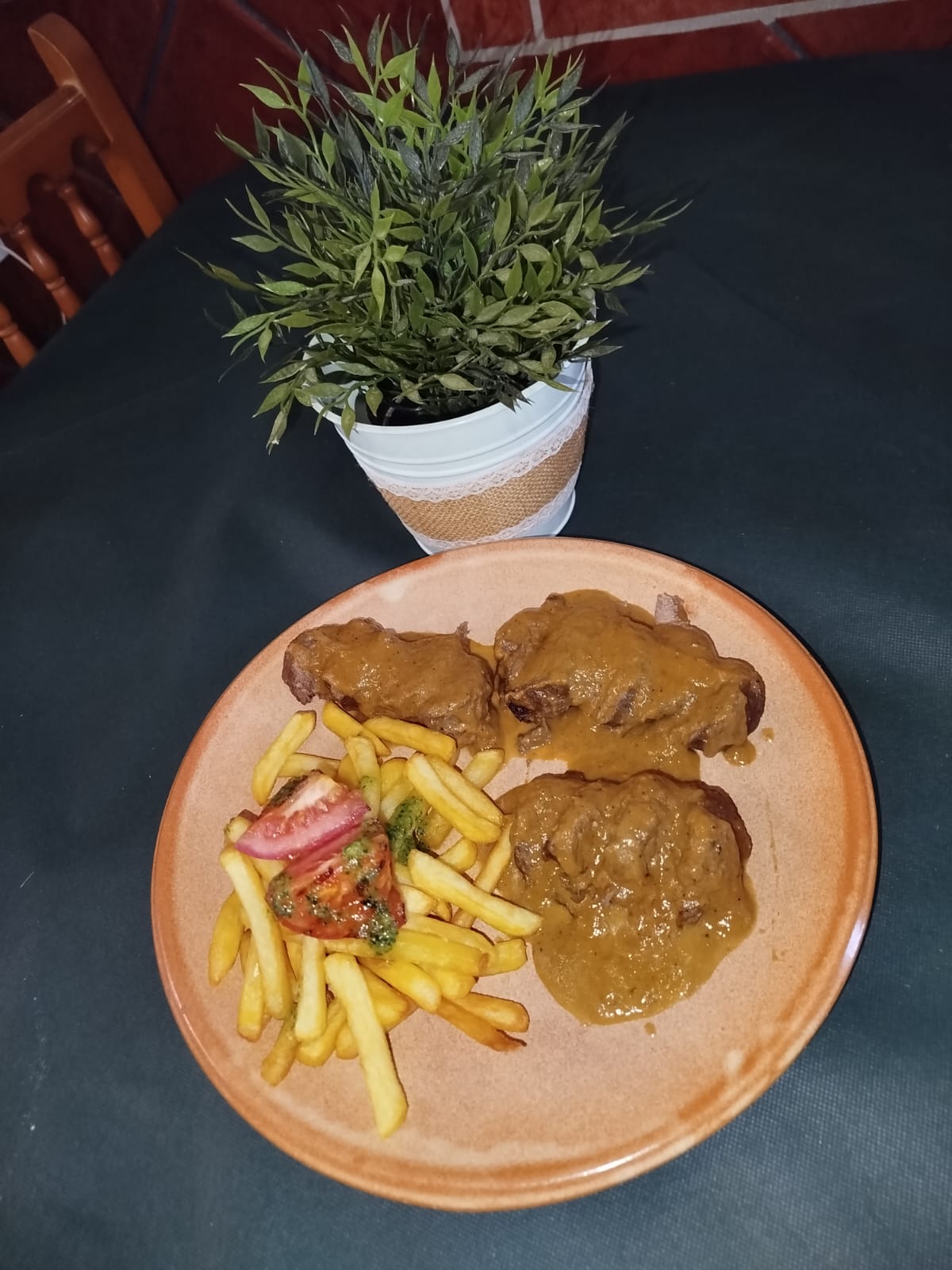 Carrillada al vino tinto con patatas fritas en plato de barro