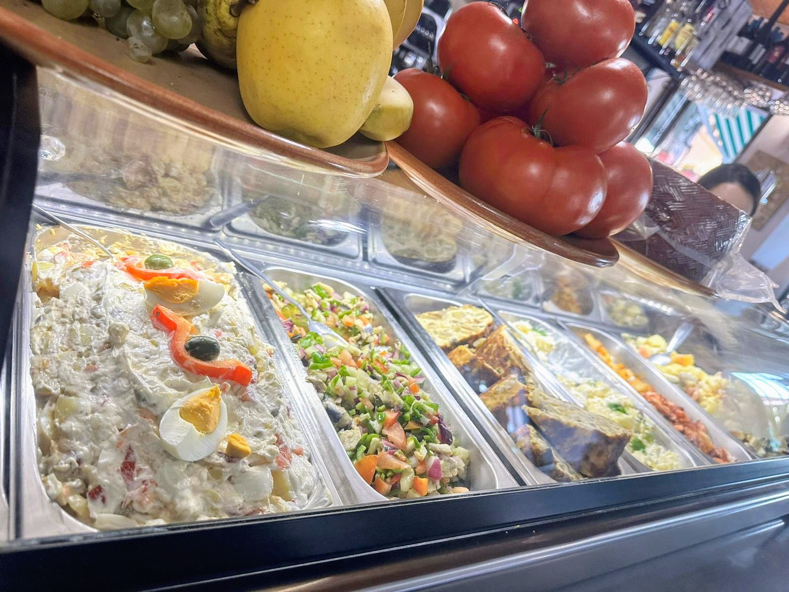 Vitrina de tapas del bar con ensaladilla, ensaladas y pimientos